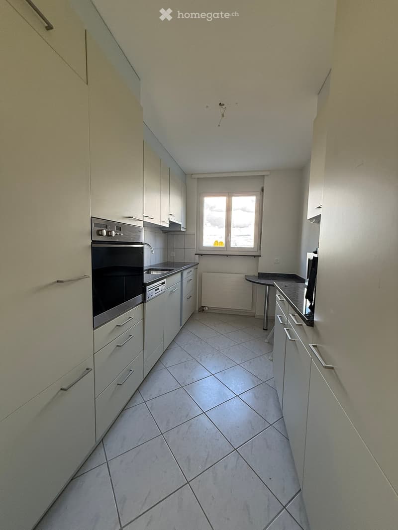 modern kitchen with tiled floor, integrated appliances, white cabinets, window, gas stove, dishwasher, washing machine, black countertops