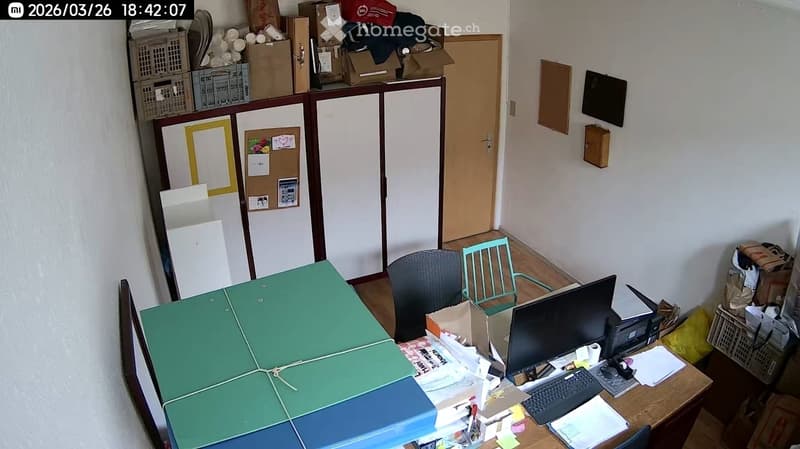 desk with computer, chairs, storage boxes, bulletin board, cabinets