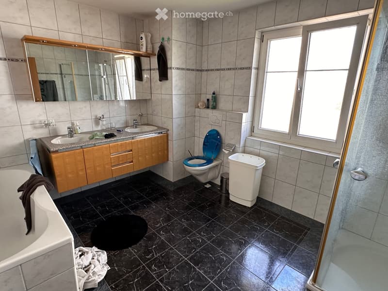 Bathroom with bathtub, sink, toilet, and shower. Tiled floor and walls.