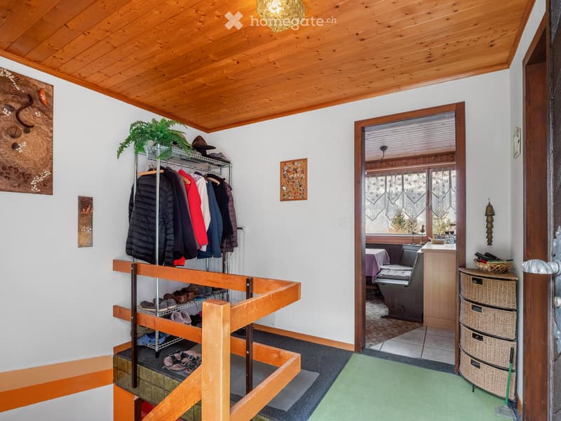 wooden ceiling, white walls, wooden rack with clothes, wooden stairs, green rug, wooden cabinet with drawers