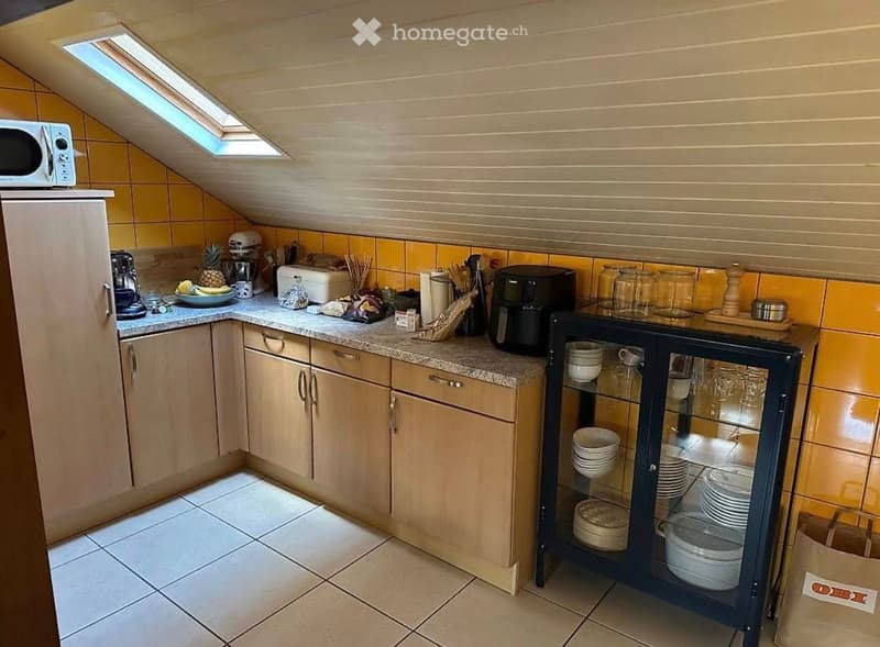 small kitchen with wooden cabinets, granite countertop, microwave, coffee maker, toaster, blender, plates, bowls, and other kitchen utensils