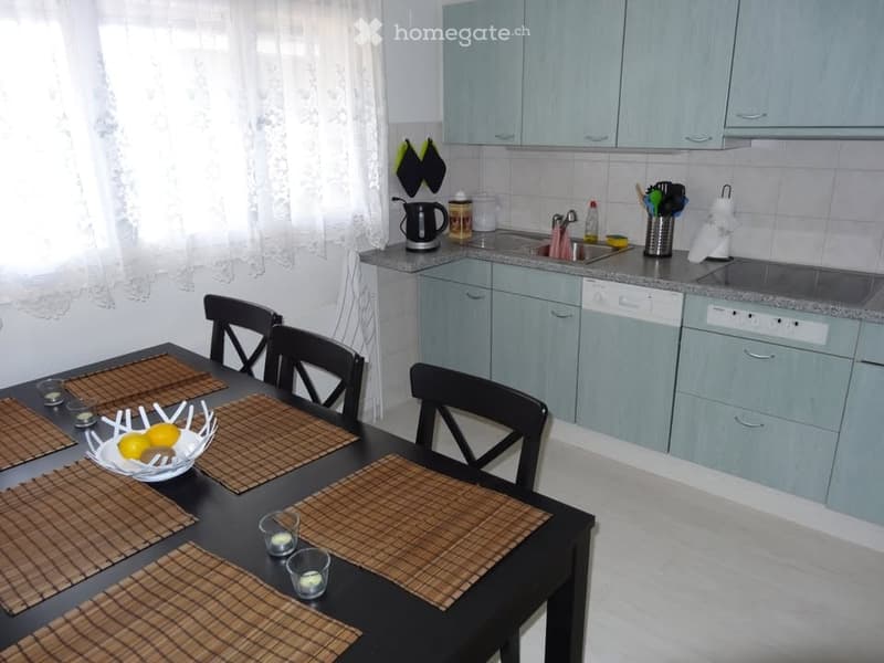 kitchen with dining area, black dining table, blue cabinets, tiled backsplash, sink, dishwasher