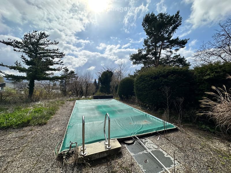 covered swimming pool, gravel ground, metal handrails, bushes, trees