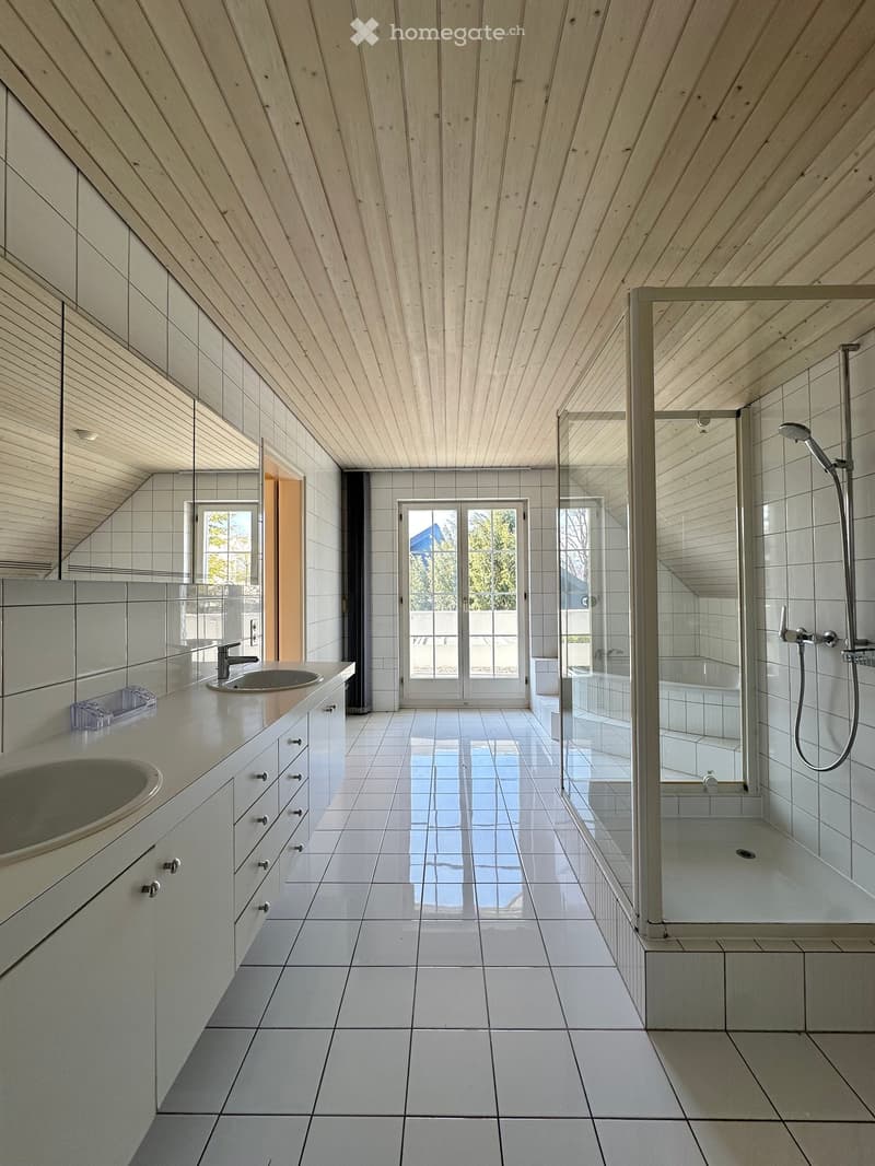 white tiled floor, white tiled walls, two sinks, large mirror, glass shower enclosure, shower head, bathtub