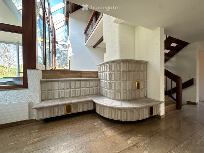 Fireplace, bench seating, wooden floor, white walls, large windows, staircase