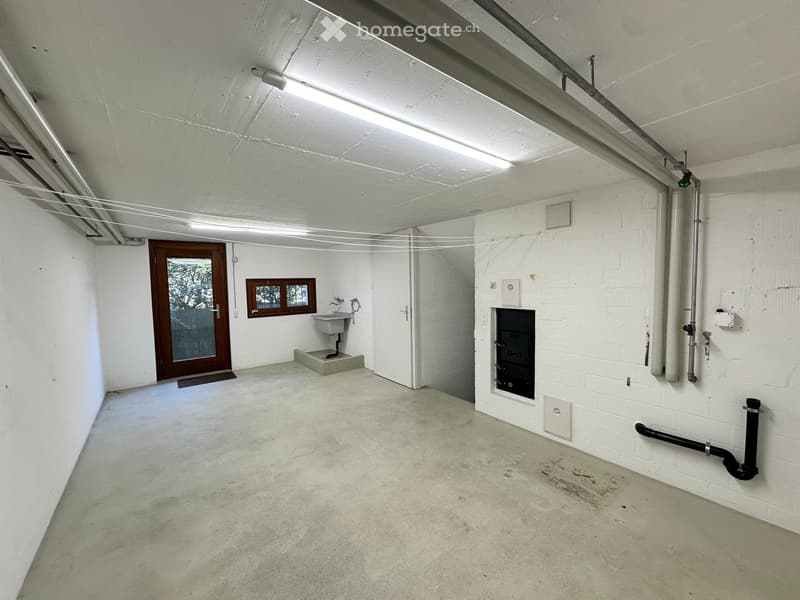 Empty room with white walls, concrete floor, a sink, a door, and a fireplace.