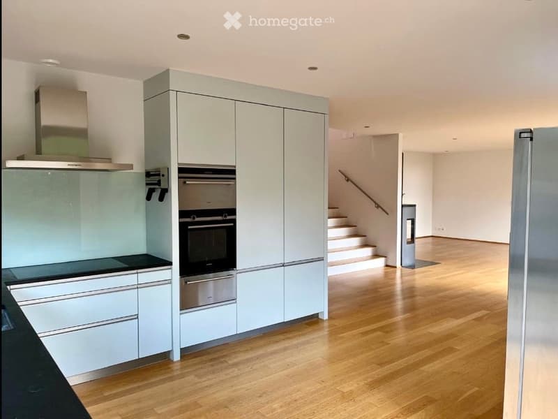 modern kitchen with white cabinets, wooden floor, built-in oven and refrigerator, range hood