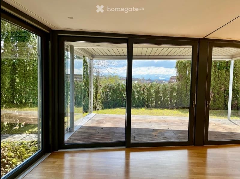 large sliding glass doors, wooden floor, wooden deck, grassy area, trees, mountains in the distance