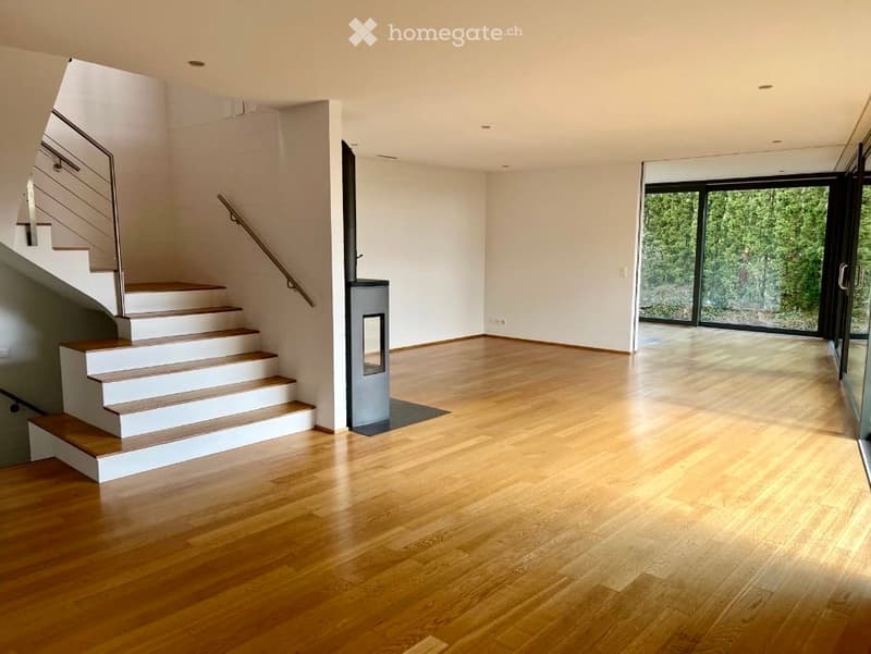 wooden floor, white walls, staircase, fireplace, glass doors, view of trees