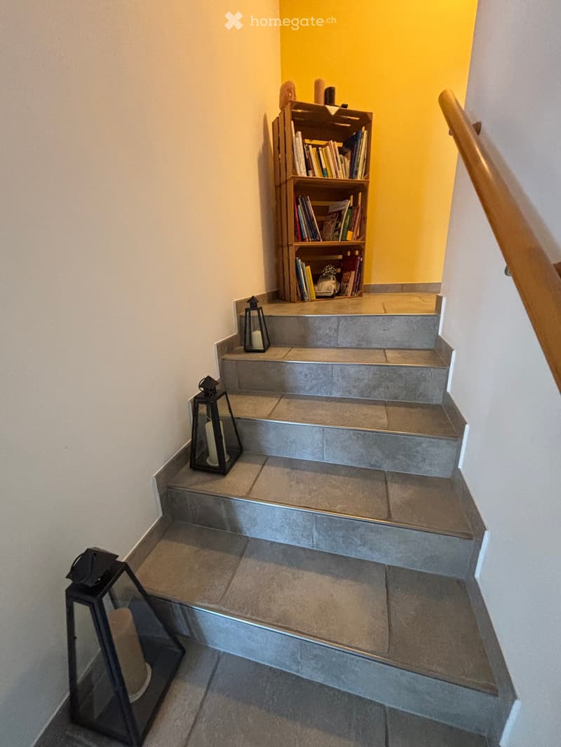 concrete stairs with three black lanterns on each step, wooden bookshelf near stairs, yellow wall