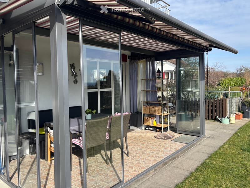 Sliding glass doors, retractable awning, patio furniture, indoor plants