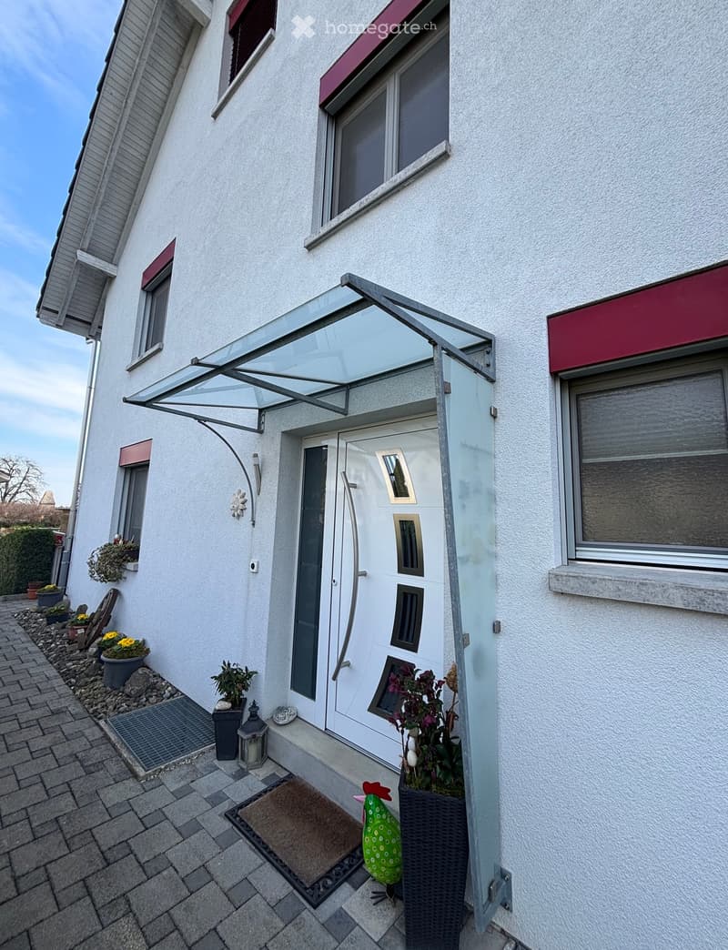 House exterior, white facade, red trims, glass canopy, white door, brick pathway, potted plants