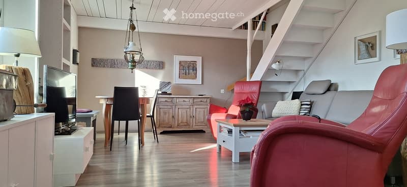 living room with wooden floor, red armchair, gray sofa, wooden table, TV, wooden cabinet, staircase