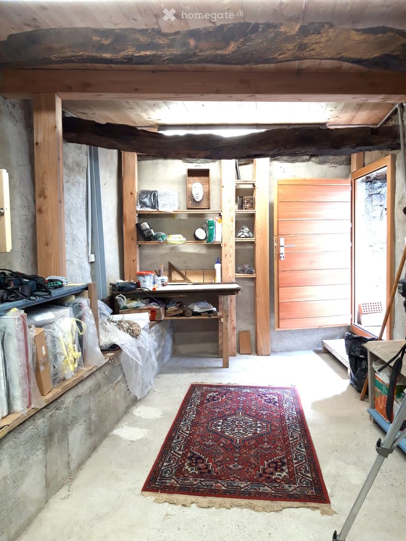 room with wooden beams, shelves, workbench, rug, tools, plastic bags, storage boxes, ladder