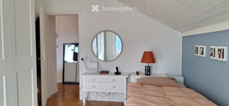 Bedroom with bed, nightstand, mirror, and wooden floor.