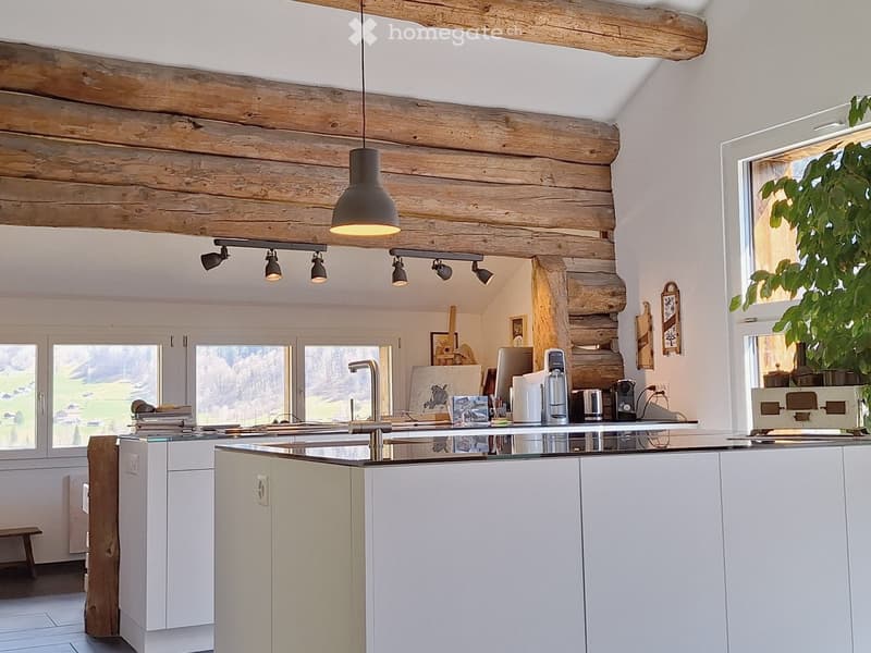 modern kitchen with white cabinets, glass countertop, wooden beams, track lighting, modern appliances, large windows