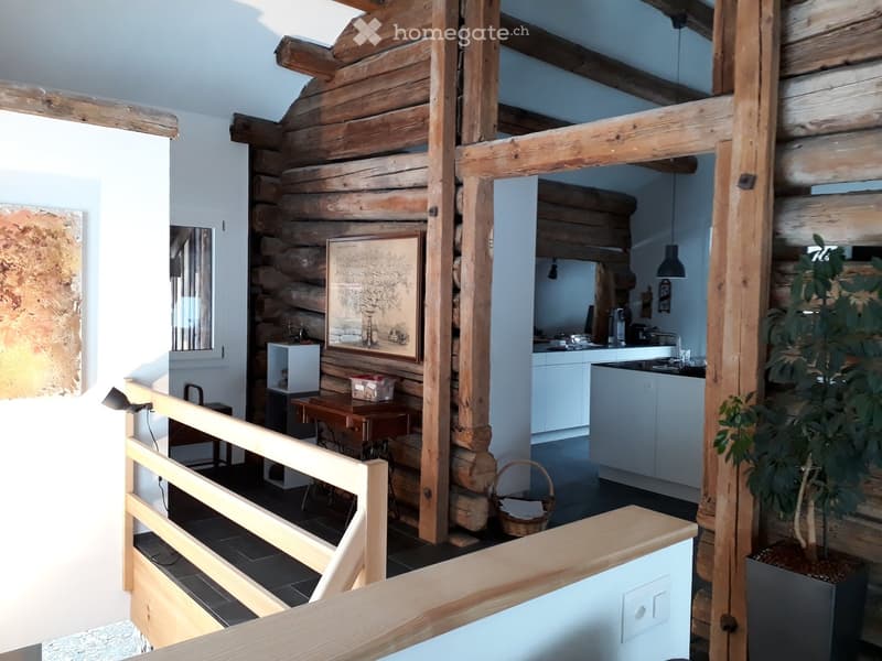 wooden walls, wooden beams, wooden railing, wooden table, picture frame, kitchen area, white cabinets, countertop, sink, faucet, basket, potted plant