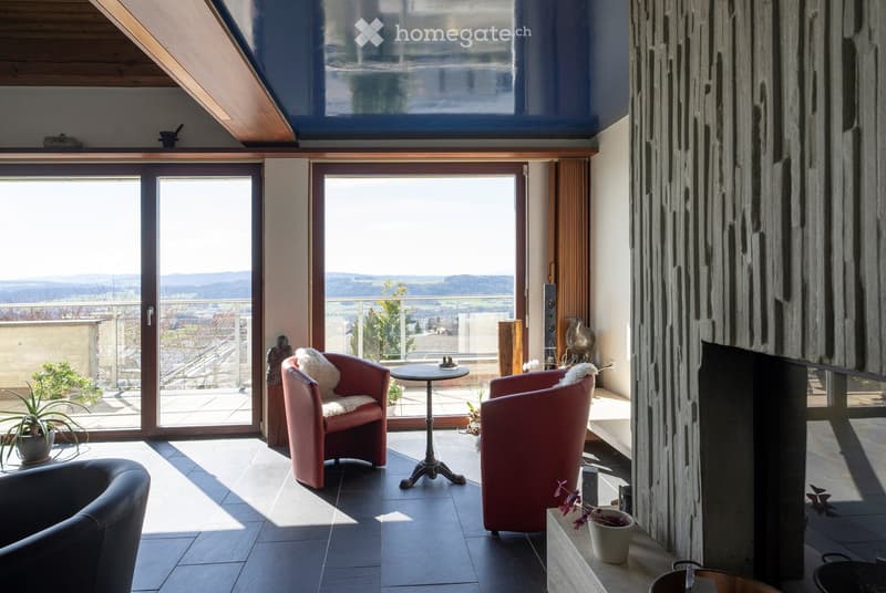 living room with fireplace, large windows, balcony, red chairs, table, plants