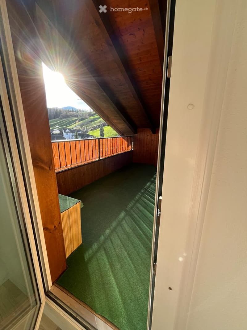 Balcony with wooden railing, green carpet, wooden ceiling, sunlight