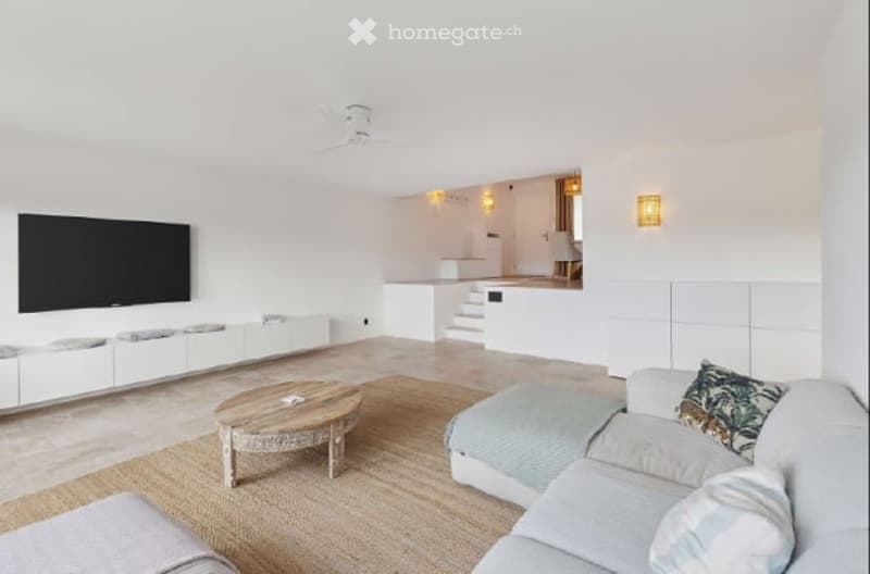 modern living room with white walls, beige carpet, white couch, wooden coffee table, flat screen TV, white cabinets, ceiling fan