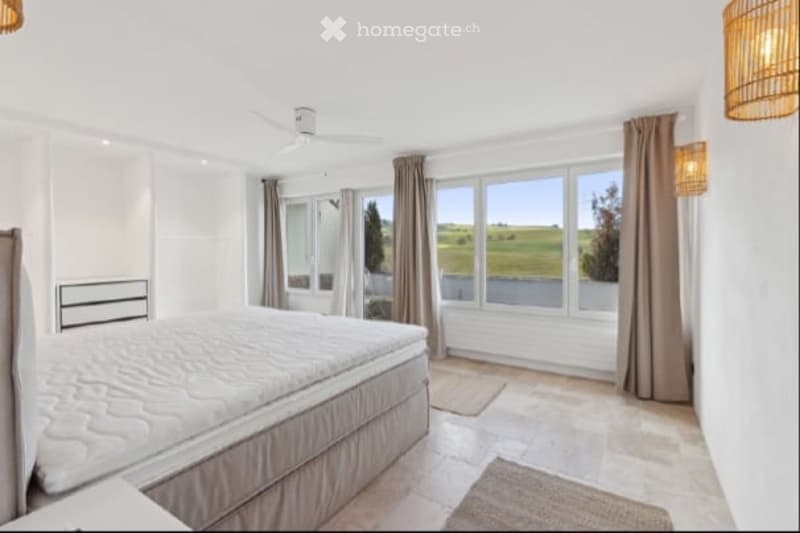 large bed, white walls, large windows, beige carpet, ceiling fan, view of the countryside