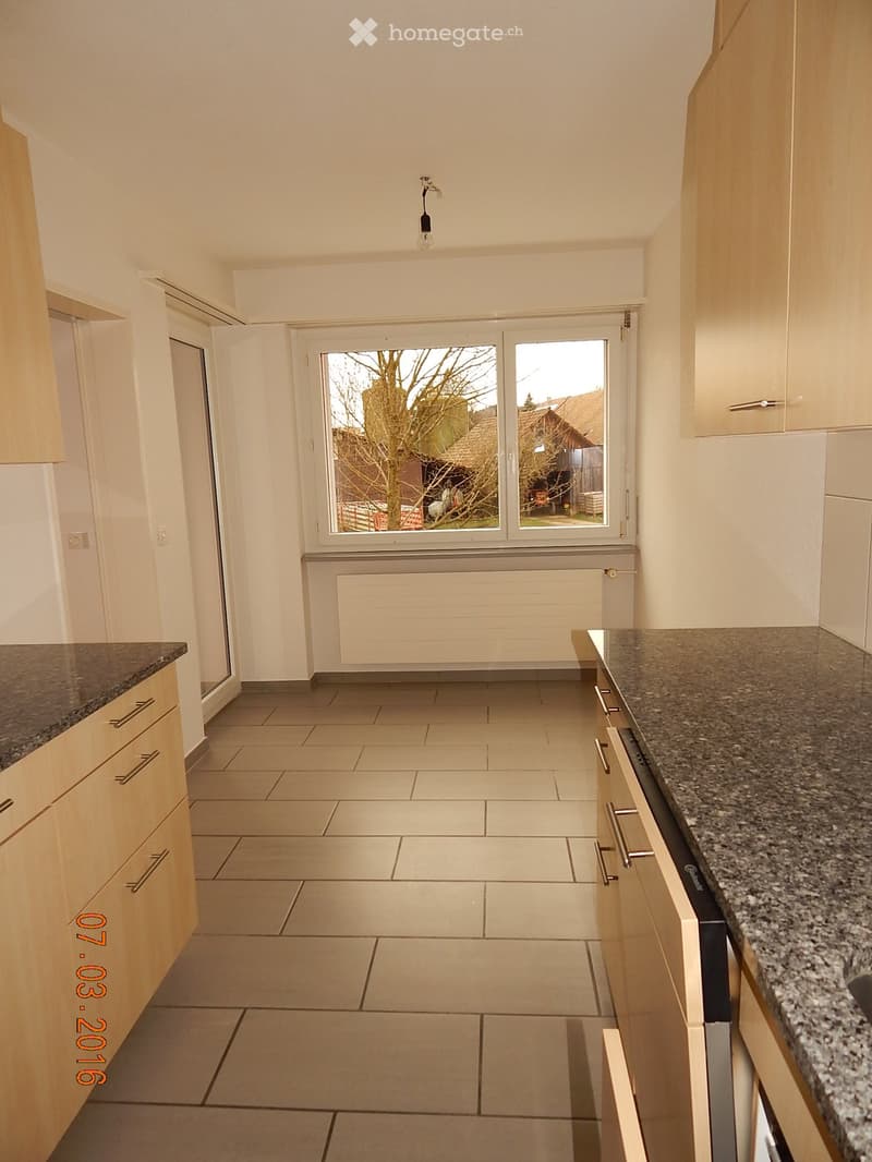 An empty kitchen with a window with a view of the outside