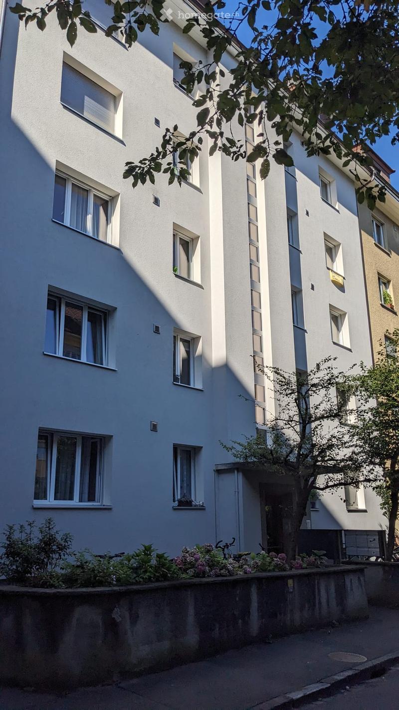 4 story building, white exterior, multiple windows, plants and flowers in front