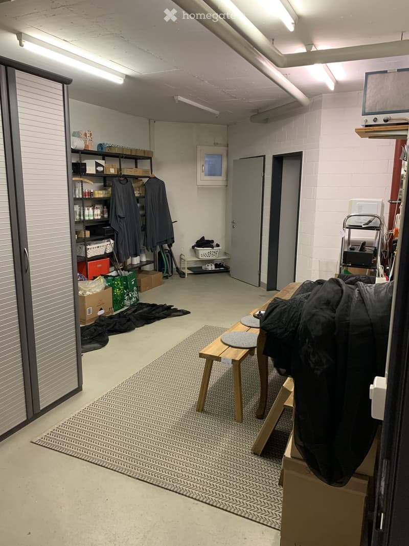 Storage room with shelves, boxes, and a rug. A wooden bench and table are placed on the rug.