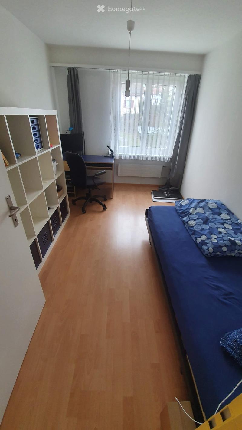 bedroom with desk and chair, blue bed, window with curtains