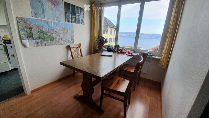 room with a wooden table and chairs, wall maps, and a large window with a sea view