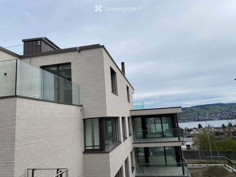 Modern building with glass balconies, brick walls, and a view of the lake