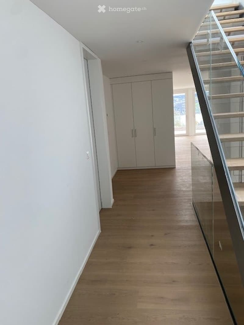 Empty hallway with wooden floor, white walls, glass staircase, white wardrobe