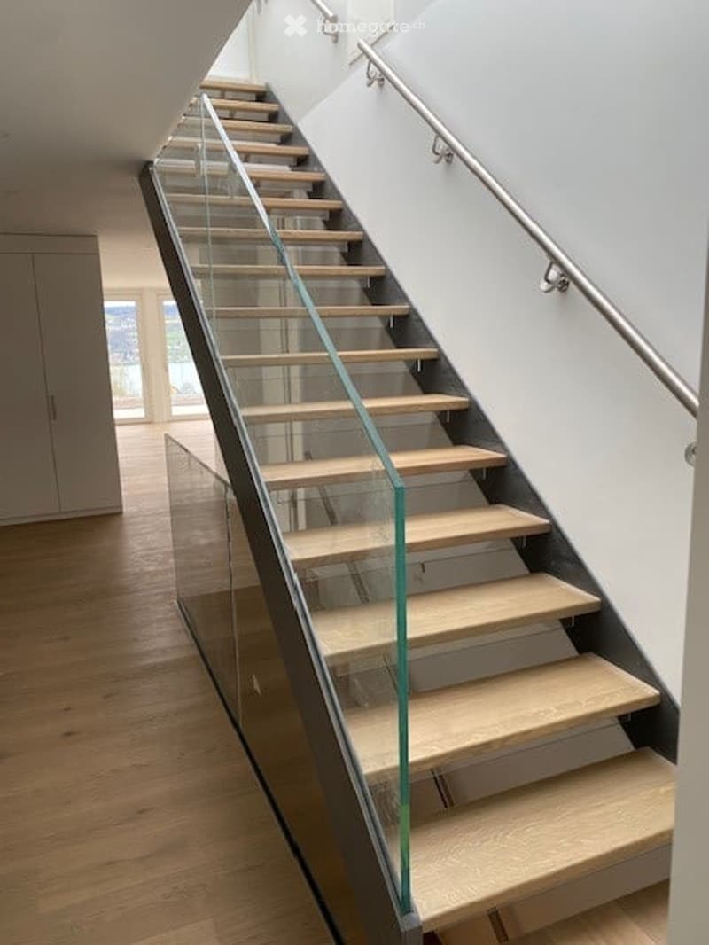 Modern staircase with glass railings and wooden steps