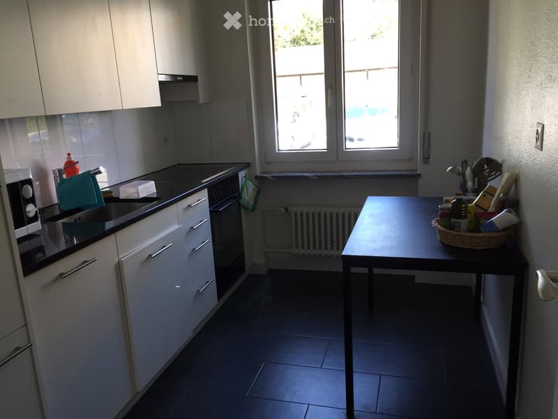 modern kitchen with white cabinets, black countertops, dishwasher, washing machine, window, radiator
