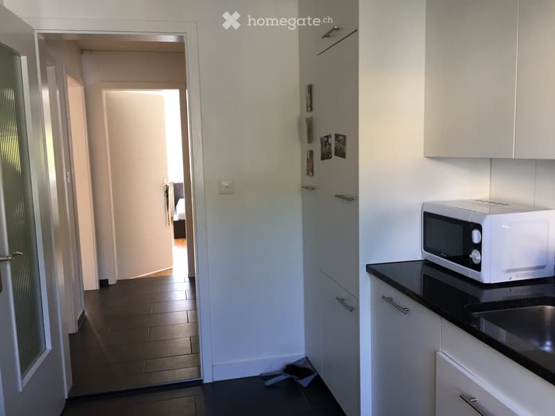 kitchen with white cabinets, black tiled floor, white microwave, sink, and countertop