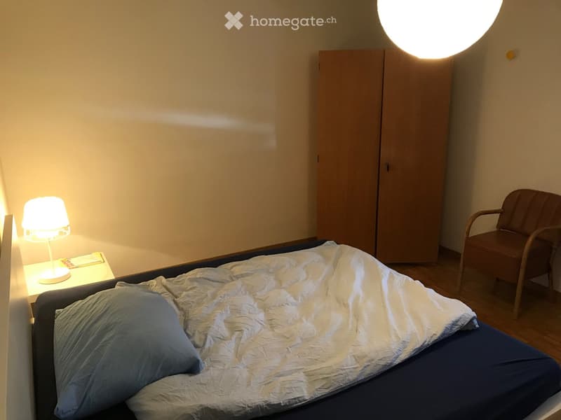 Bedroom with bed, lamp, nightstand, wardrobe, and chair