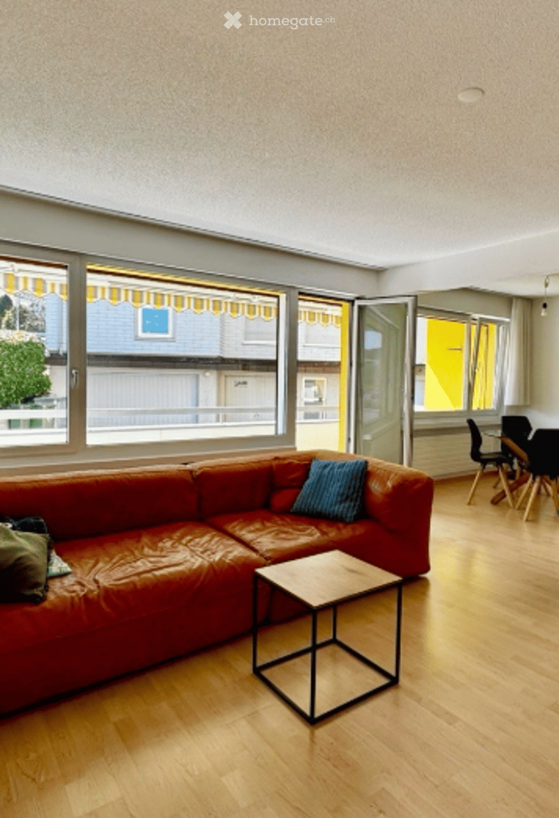 large windows, balcony, red leather couch, wooden coffee table, wooden floor