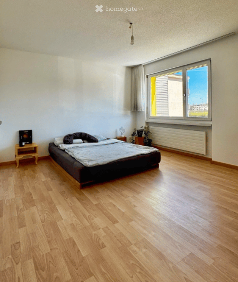 Bedroom with bed, nightstand, plants, window, radiator, wooden floor