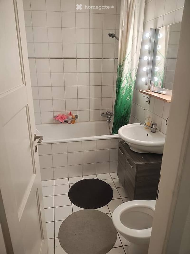 Bathroom with bathtub, sink, toilet, and mirror with lights