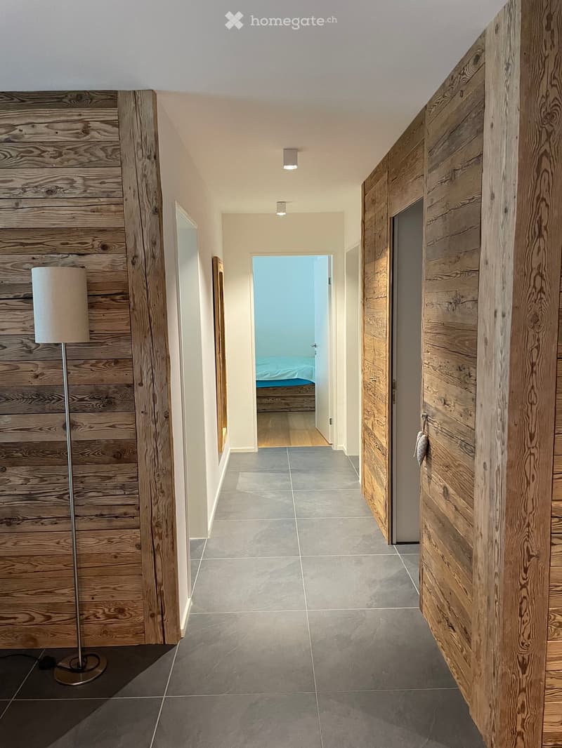 wooden walls, tiled floor, hallway, lamp, open door, bed visible