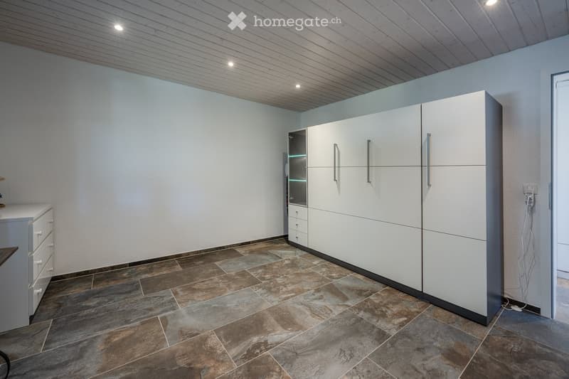 Empty room with white walls, tiled floor, built-in cabinets, and a small cabinet on the left side.