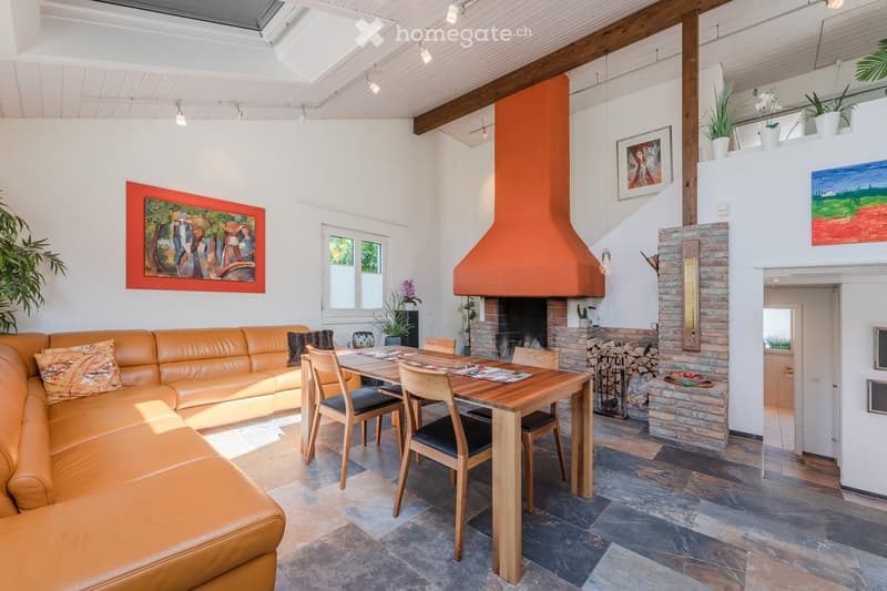 modern living room with fireplace, dining table, leather couch, wooden floor, paintings, plants