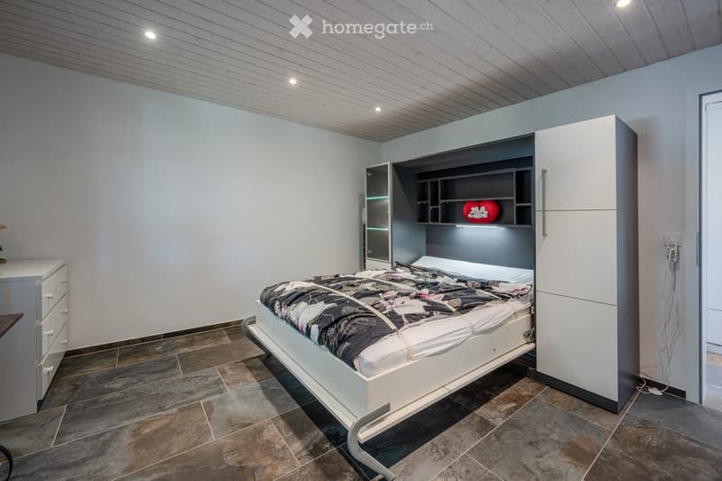 modern bedroom with a bed, built-in wardrobe, tiled floor, white walls, ceiling lights, and a small table