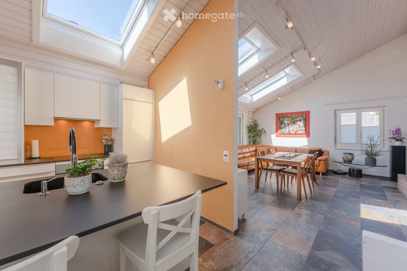 modern kitchen with island, skylights, dining area, living room with couch, table, and painting