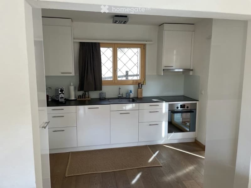 modern kitchen with white cabinets, black countertops, stainless steel appliances, wooden floor, window with curtains