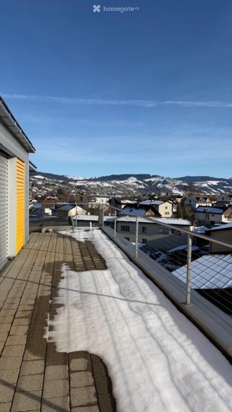 Roof terrace with snow, metal railing, view of the city and mountains