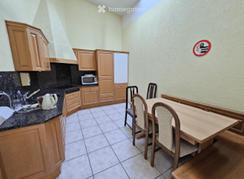kitchen with dining area, wooden cabinets, white tiled floor, dining table with chairs, microwave, kettle, sink