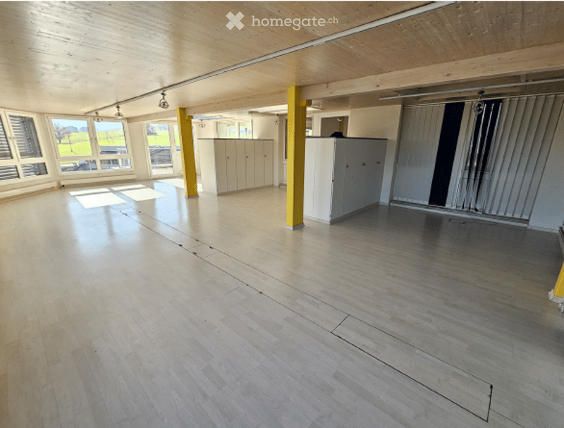 empty room, wooden floor, yellow pillars, white cabinets, large windows
