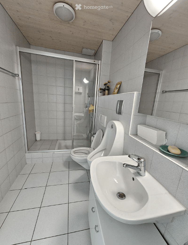 white tiled floor, white walls, glass shower enclosure, white toilet, white sink, mirror, soap dish, tissue holder