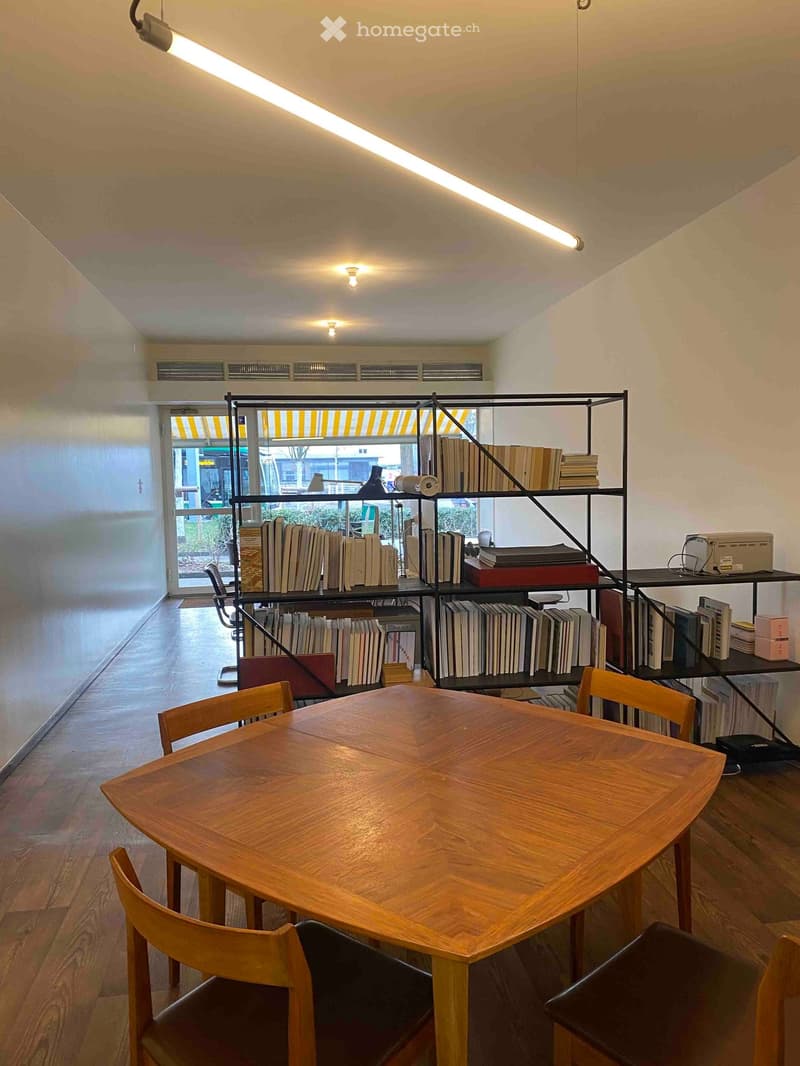 wooden table, wooden chairs, bookshelves, fluorescent ceiling lights, glass door
